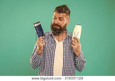 Man Bearded Hipster Choose Shampoo Or Shower Gel. Hair Care And Skin Treatment. Choose Beauty Produc