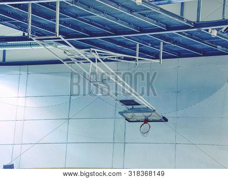 Fold Orange Basketball Hoop With White Net In Indoor Gymnasium Sport Metal Roof Background