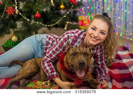 Merry Christmas And Happy New Year. A Charming Blonde Girl Lies Under The Christmas Tree And Plays W