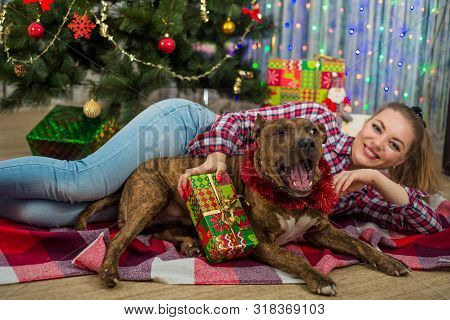 Merry Christmas And Happy New Year. A Charming Blonde Girl Lies Under The Christmas Tree And Plays W