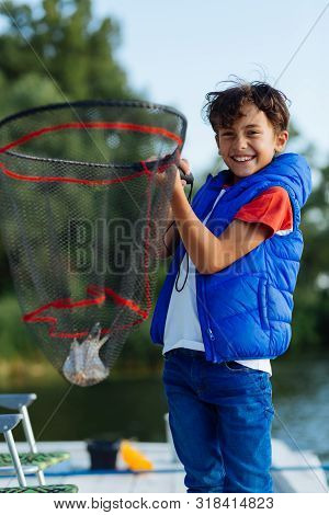 Happy Beaming Boy Holding Fishing Net With Little Fish