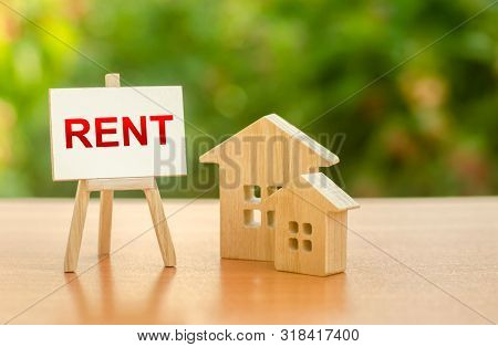 Two Figures Of Houses And An Easel With The Word Rent. The Concept Of Temporary Rental Housing And R