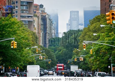 Manhattan Buildings Skyline From 5th Ave. Harlem In A Foggy Day, Through The Trees And Traffic Light