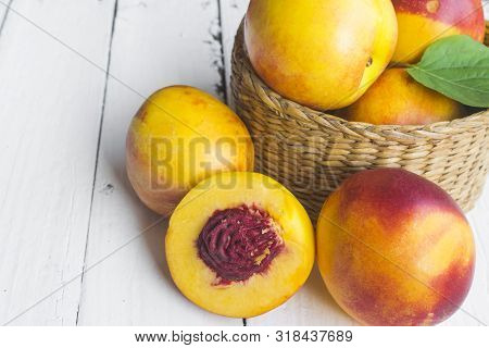 Delicious And Juicy Peach (nectarina) In Basket  On White Wooden Table With Place For Text