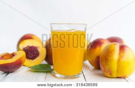 Delicious And Juicy Peach (nectarina) With Glass Of Juice On White Wooden Table.