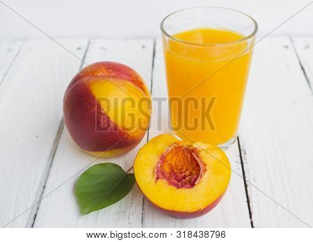 Delicious And Juicy Peach (nectarina) With Glass Of Juice On White Wooden Table.