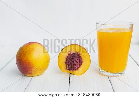 Delicious And Juicy Peach (nectarina) With Glass Of Juice On White Wooden Table.