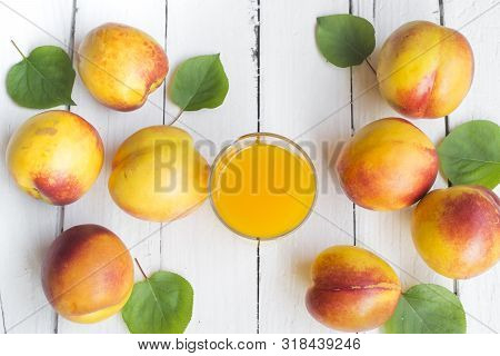 Delicious And Juicy Peach (nectarina) With Glass Of Juice On White Wooden Table.