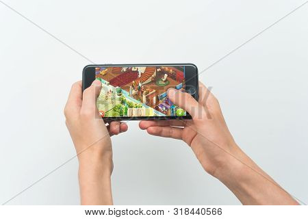 Samara, Russia -07, 29, 2019: A Young Guy Playing Homescapes Game On Iphone 8 Plus. Teenage Boy Hold