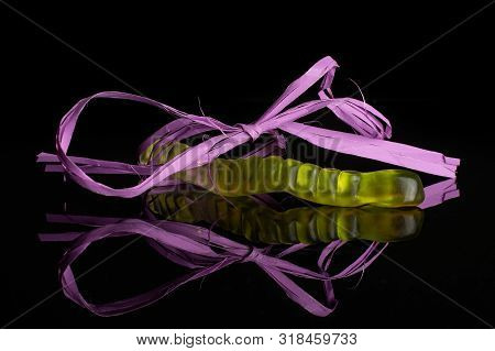 One Whole Colourful Jelly Worm Candy Tied By Violet Ribbon Isolated On Black Glass
