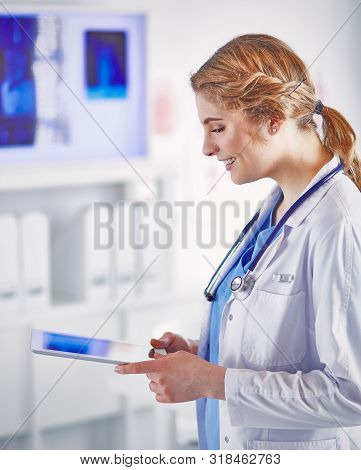 Young Woman Doctor Is Standing With Board With Clipboard Smilin