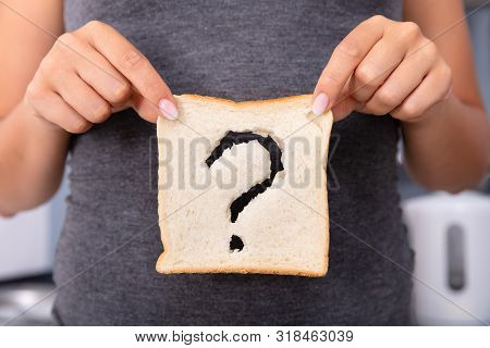 Mid-section Of A Woman Hands Holding Sliced Bread With Question Mark Sign