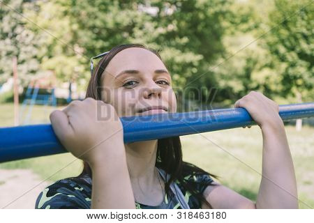 A Young Handsome Woman In Casual Clothes Is Doing Pull Up Exercise On Horizontal Bar. Fitness, Sport