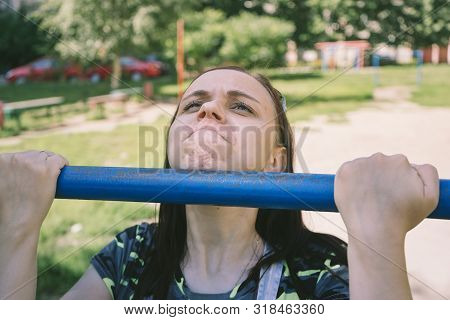 A Young Handsome Woman In Casual Clothes Is Doing Pull Up Exercise On Horizontal Bar. Fitness, Sport