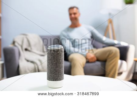 Close-up Of Wireless Speaker In Front Of Man Sitting On Sofa
