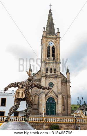 Turmeque, Colombia - August, 2019: Our Lady Of Chiquinquira Church And The Monument To Chaquen The G