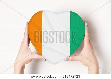 Flag Of Côte D'ivoire On A Heart Shaped Box In A Female Hands. White Background