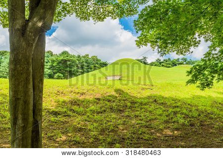 Songsan-ri Tombs In Gongju Under Beautiful Blue Sky With Large White Puffy Clouds.