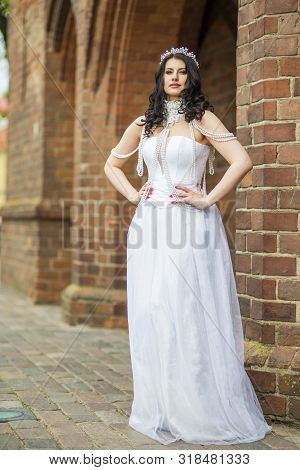 Full Length Portrait Of Tranquil Sensual Caucasian Bride With Crown And Necklace Posing Against Old 