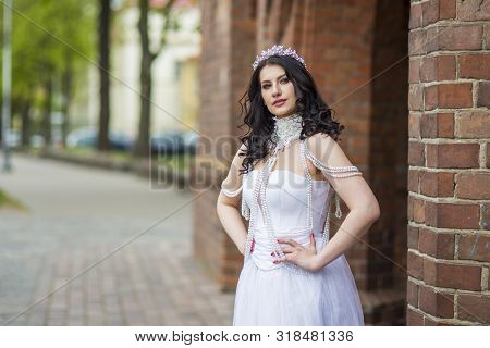 Portrait Of Tranquil Sensual Caucasian Bride With Crown And Necklace Posing Against Old Brick Wall O