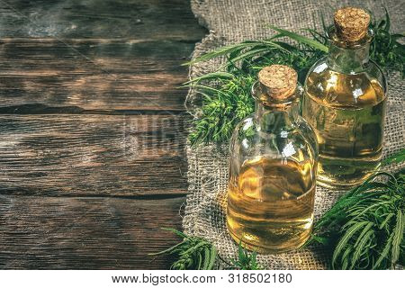 Cbd Oil Bottles And Green Plant Of Cannabis On A Wooden Background. Herbal Medicine.