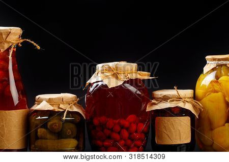 Glass Bottle With Preserved Food On Black Background