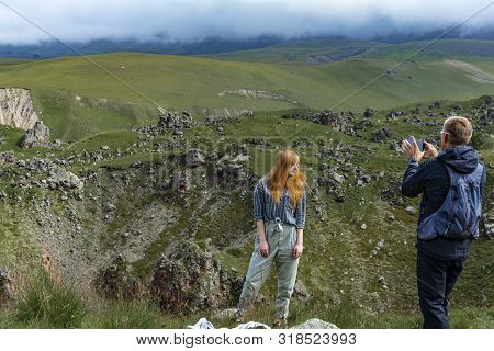 Green Alpine Meadow On The Slopes And Mountains In The Fog. Cloudy Day In The Mountains. A Man Photo