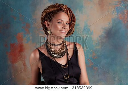 Southern Spices. A Beautiful Young Blue-eyed Woman With Afrocos And Large Ornaments Against A Textur