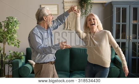 Joyful Active Old Retired Romantic Couple Dancing In Living Room