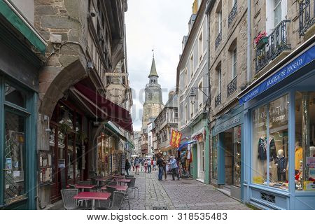 Dinan, Brittany, France - June 20, 2019: Looking along busy tourist street Rue de la Poissonnerie in Dinan on a cloudy summer day