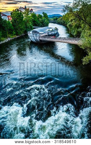 Graz, Austria - 17.08.2019: View At Mur River, Murinsel On Bridge, People Enjoy Beautiful Summer. Tr