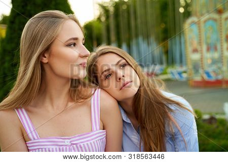Close Up Shot Of Two Charming Young Girls Having Pleasant Rest After Long Awaited Holiday In Amuseme