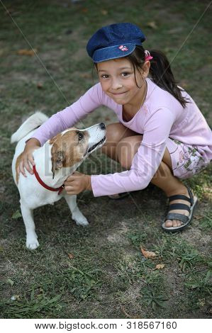 Ukraine, Pokrov - August 23, 2019: Small Fashionable Cute Girl Playing With Pet Dog Jack Russell Ter