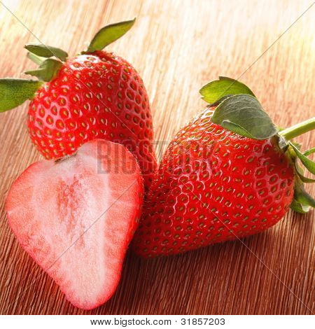 trois fraises sur terrasse en bois