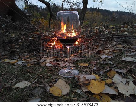 Wine Swirl With A Sky And Sunset. Wineglass With Woman Hand Swirling Rose Red Drink Outdoor During H