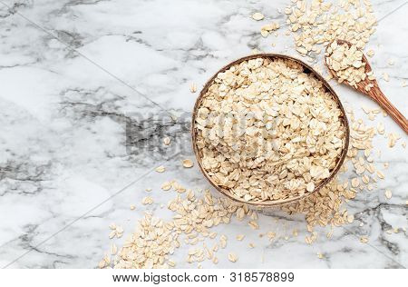Healthy Raw Uncooked Quick Oat Flakes In A Wooden Bowl Over A Marble Table Background. Shot From Top