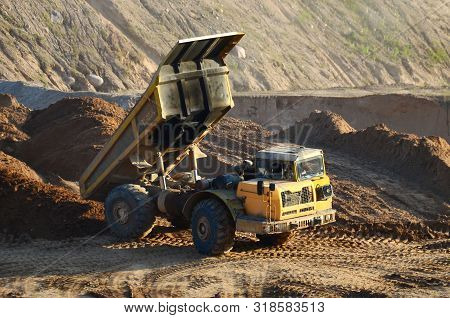 Big Yellow Dump Truck Working In An Sand Open-pit. Mining Quarry For The Production Of Crushed Stone