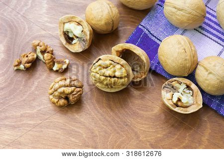 Whole Walnuts And Walnut Kernel Halves Without Shell On A Dark Wooden Table And Checkered Towel, Clo