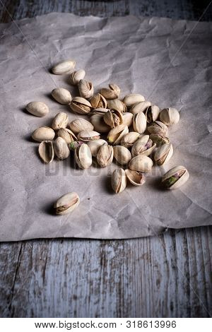 Pistachios On Wooden Table In The Foreground With Darkened Background