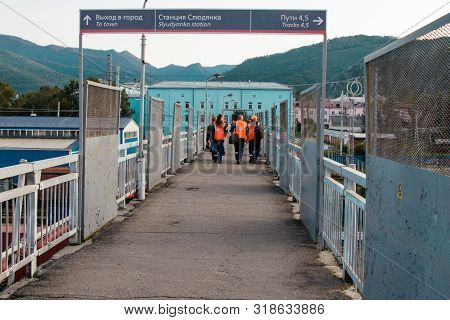 Slyudyanka, Russia - August 13, 2019: Railway Workers In Bright Special Vests Walk Along The Pedestr