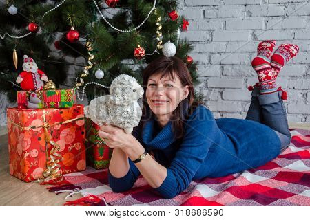 Older Adult Beautiful Brunette Woman In A Casual Style Lies In The Christmas Decorations Under The T