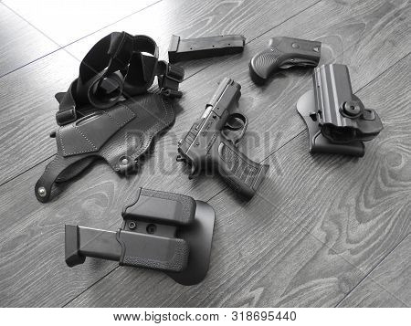Black Pistol In Holster And Magazines With Weathered Wood Backdrop