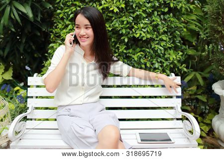 Young And Cute Asian Women Sitting And Using Cell Phone During Holiday