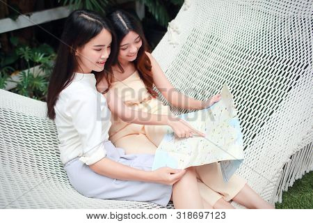 Young And Cute Asian Women Lying In A Hammock And Searching Location In A Map During Holiday