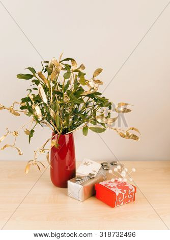 Gifts In Red And Silver Package With Mistletoe In Vase