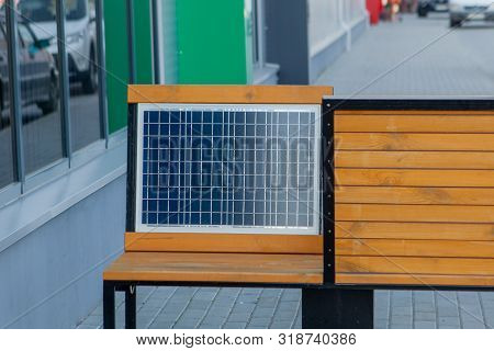 Outdoor Shot Of Wooden Bench In Park Having Solar Power Panel Installed, Usb Cabel Connected To Smar