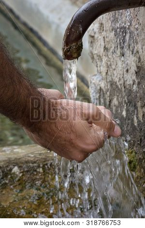 Man Hands Catching Water From A Stone Fountain.