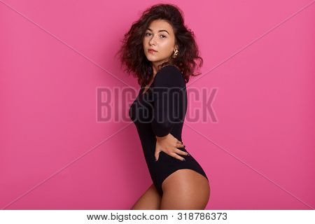 Studio Shot Of Young Slim Glamour Lady With Dark Wavy Hair Dressed In Black Combi Dress, Woman Has P
