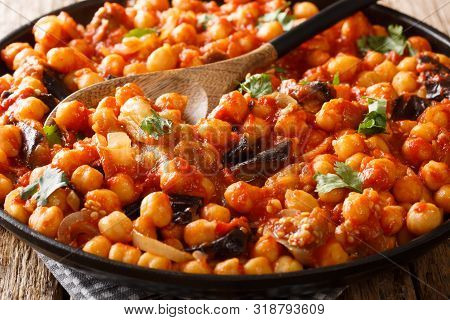 Dish Of Stewed Chickpeas With Eggplant, Tomatoes, Onions, Herbs And Spices Close-up On A Plate. Hori