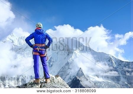 Climber Reaches The Summit Of Mountain Peak Enjoying The Landscape View.